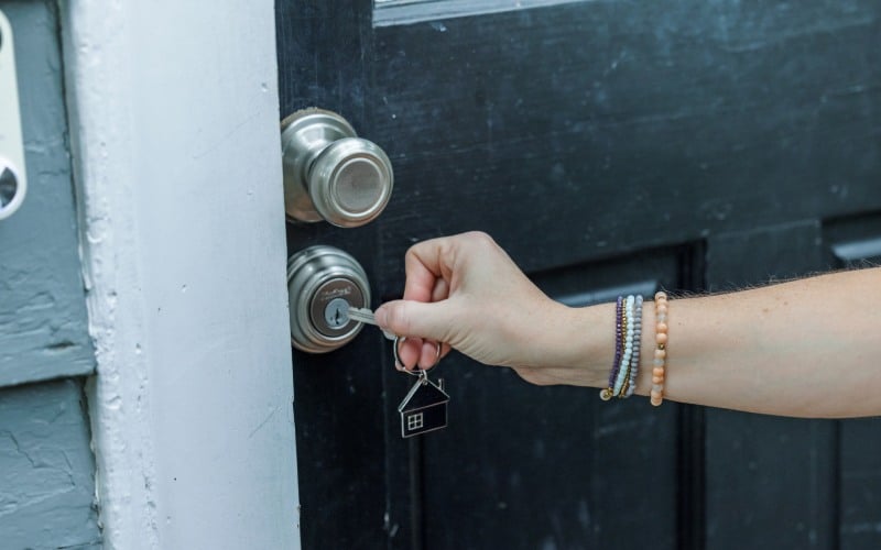 a woman opening a locked back door in the rear of a home